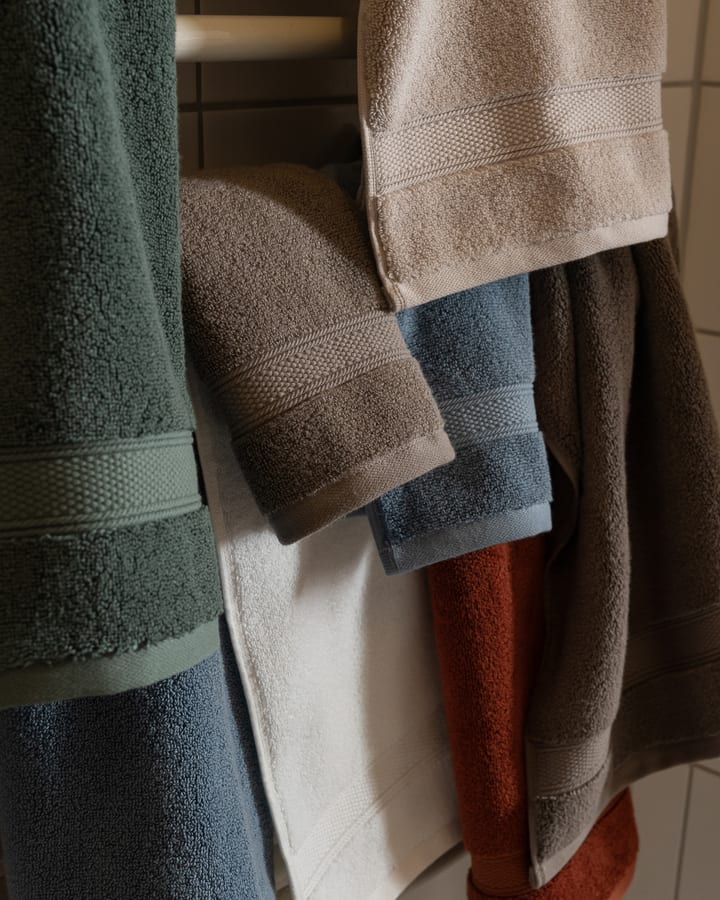 capyhome Turkish cotton towels in green, beige, cream and rust layered on a bathroom rail