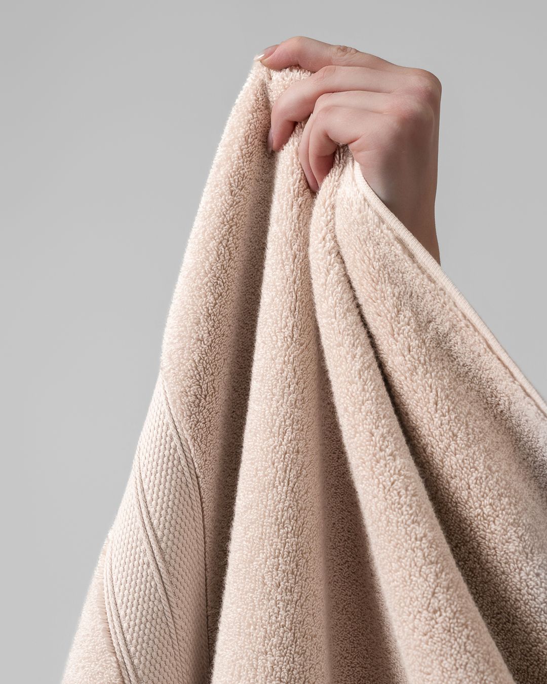 hand lifting a lightweight modal cotton bath towel by one corner