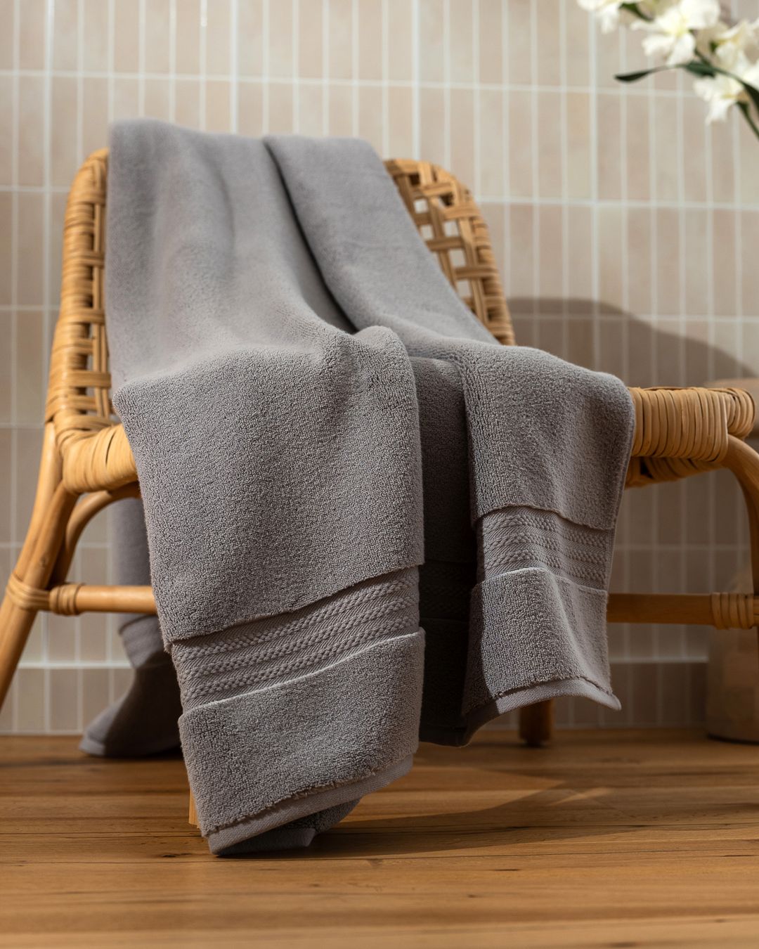 large grey capyhome bath sheet draped over a rattan chair, showing its extra length