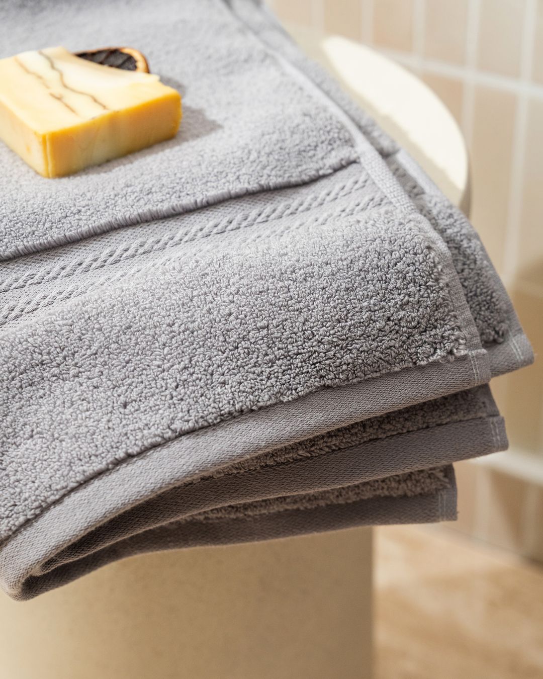 folded grey guest towels stacked with a bar of soap resting on top