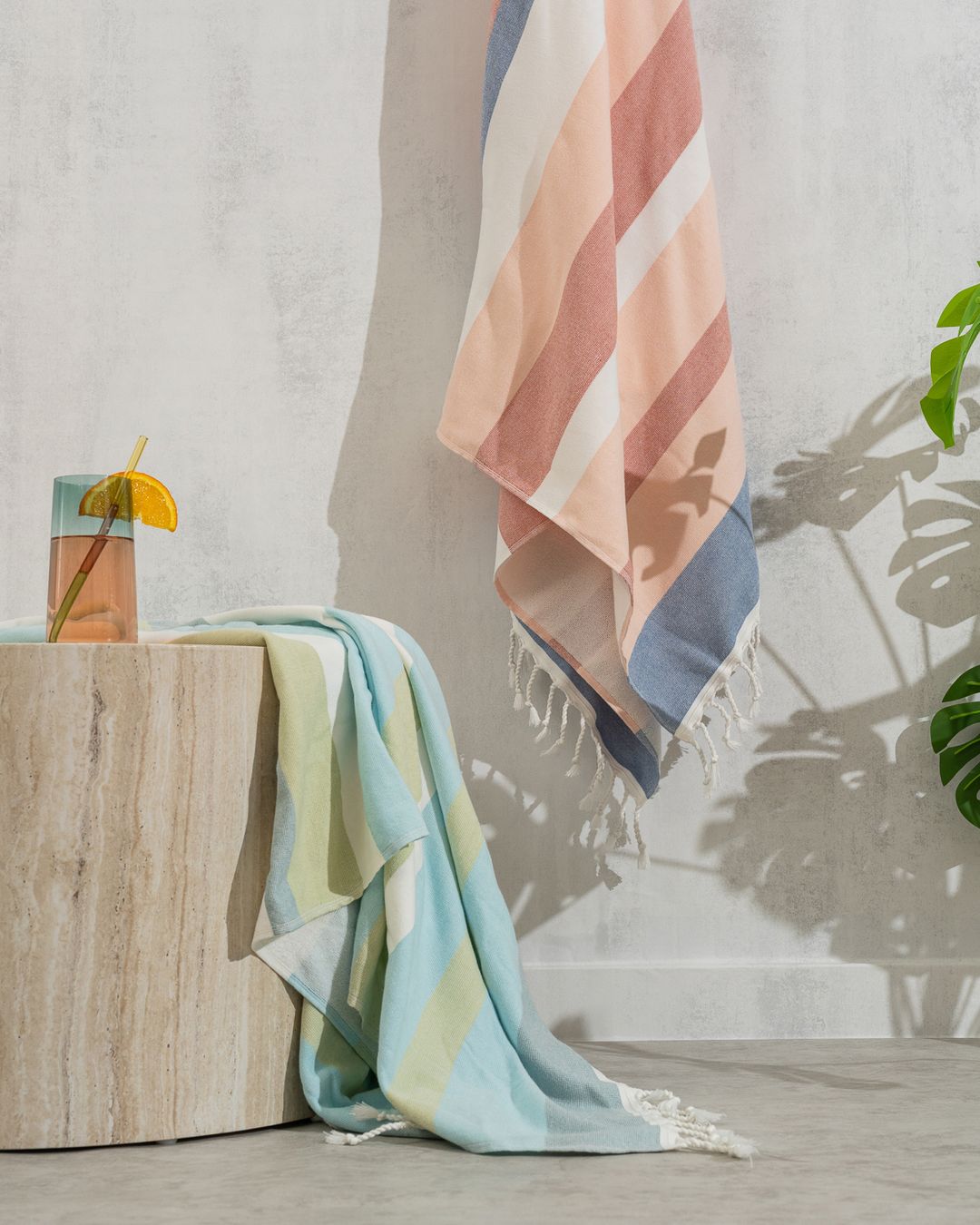 striped Turkish peshtemal towels with tasseled edges, one hanging on a wall and one draped over a stone stool