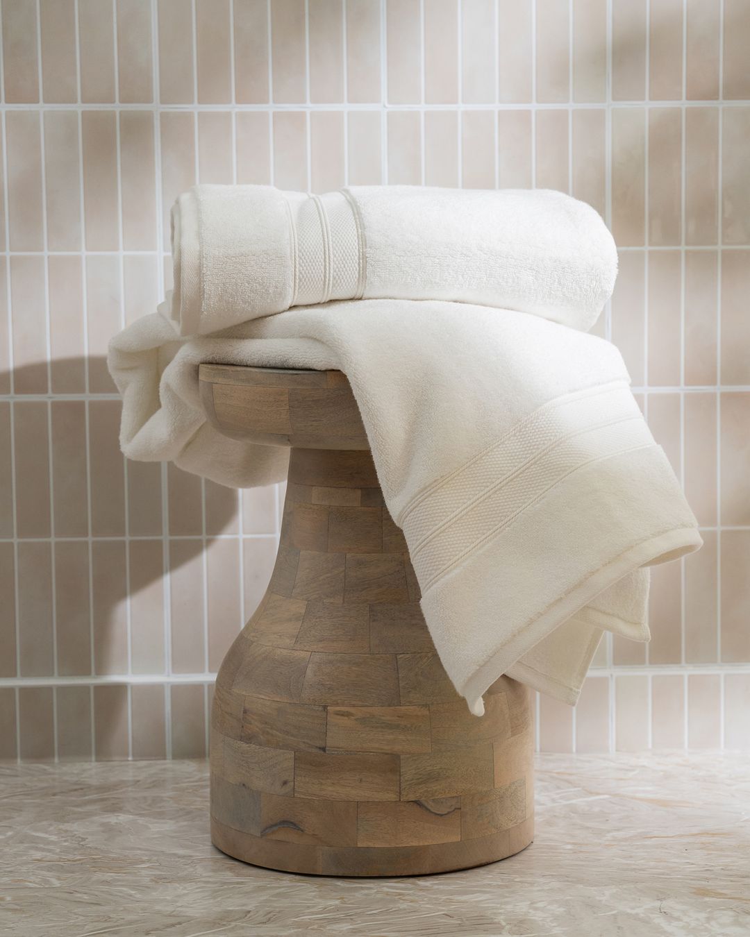 white capyhome bath towels folded on a wooden stool