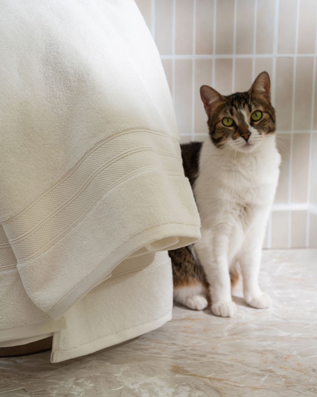 white modal cotton bath towel hanging in a tiled bathroom to dry between uses