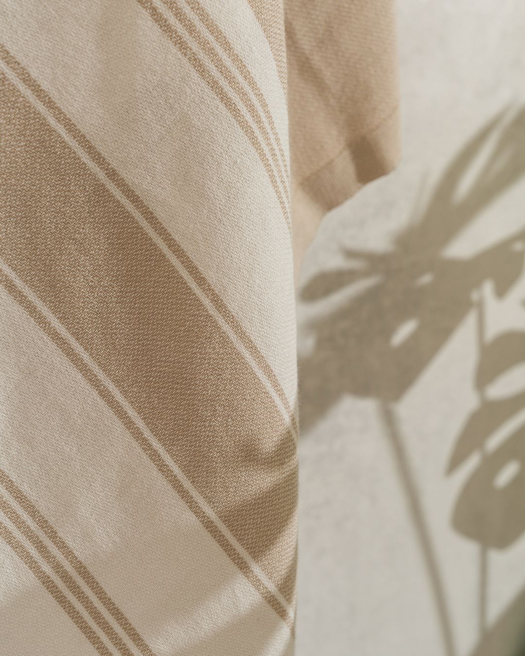 close-up of a flat-woven Turkish peshtemal towel with beige and cream stripes and no loops, hanging in sunlight
